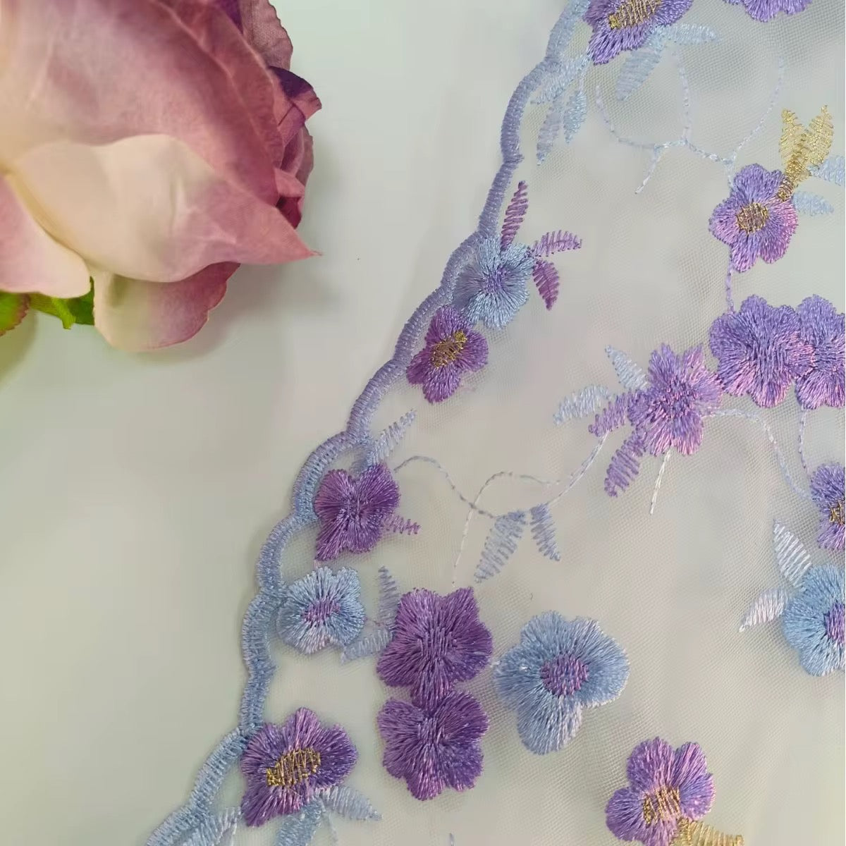 Detalle de adorno de encaje con bordado floral multicolor
