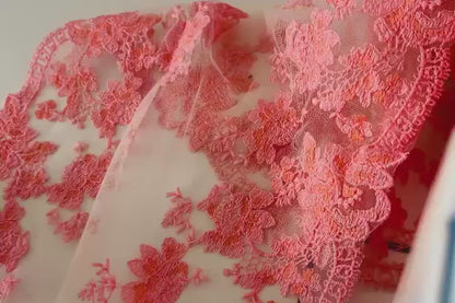 Vista completa de encaje bordado con patrón de hojas y flores rosa
